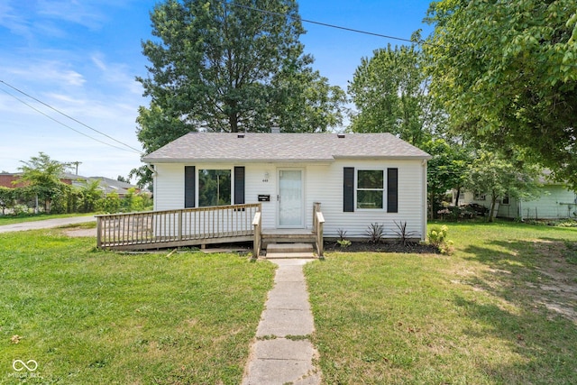 view of front of house with a wooden deck, a front yard, and roof with shingles