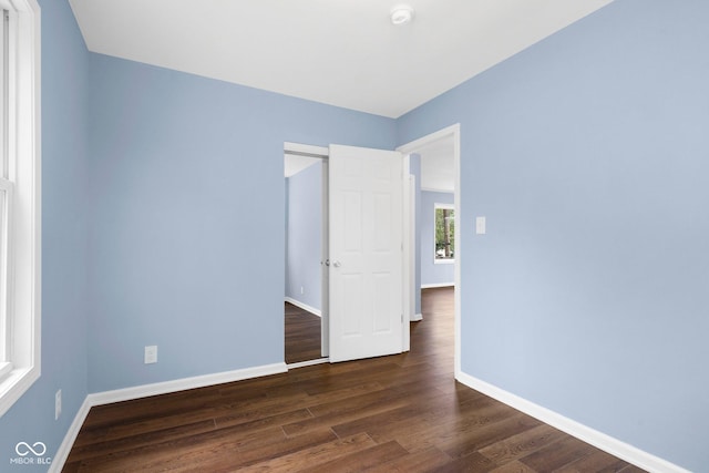 unfurnished room featuring baseboards and dark wood-style flooring