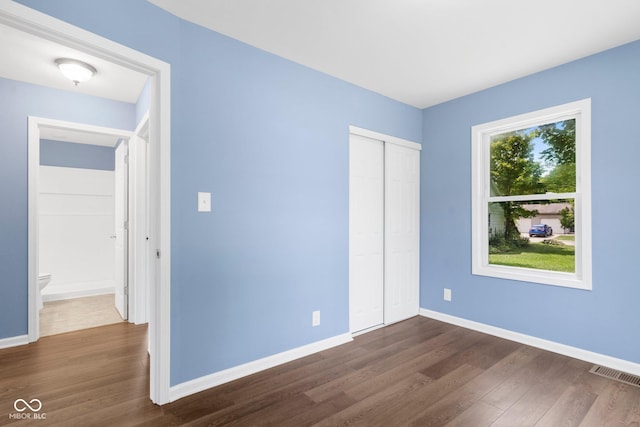 unfurnished bedroom with visible vents, dark wood-type flooring, and baseboards