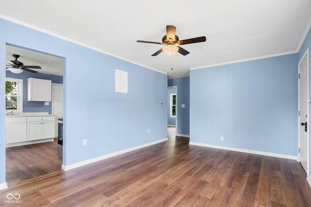 spare room featuring dark wood finished floors, baseboards, ceiling fan, and ornamental molding