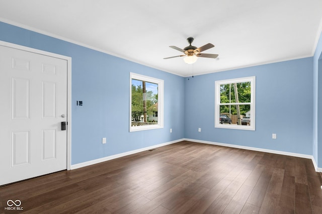 spare room with ornamental molding, dark wood-style floors, baseboards, and ceiling fan