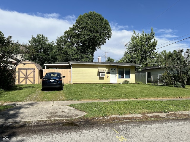 view of front of property featuring cooling unit, a front lawn, and a storage shed