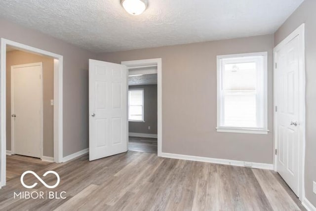 unfurnished bedroom with a textured ceiling and light wood-type flooring