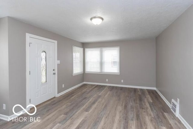 entryway with wood-type flooring and a textured ceiling