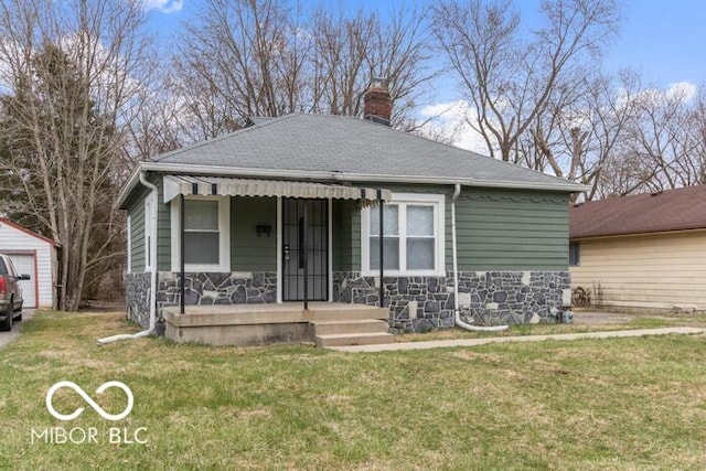 bungalow-style home with stone siding, a chimney, a front yard, a shingled roof, and a porch