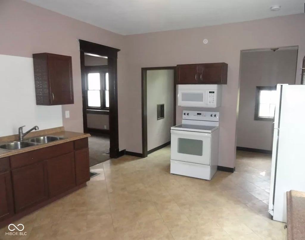 kitchen featuring sink, plenty of natural light, white appliances, and light tile floors