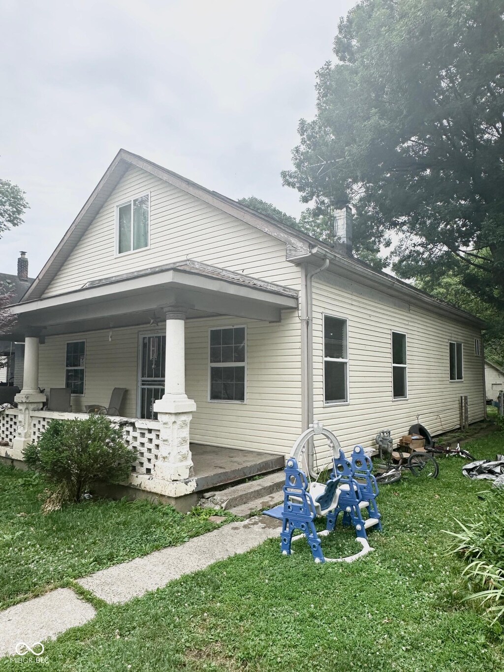 back of property with covered porch and a lawn