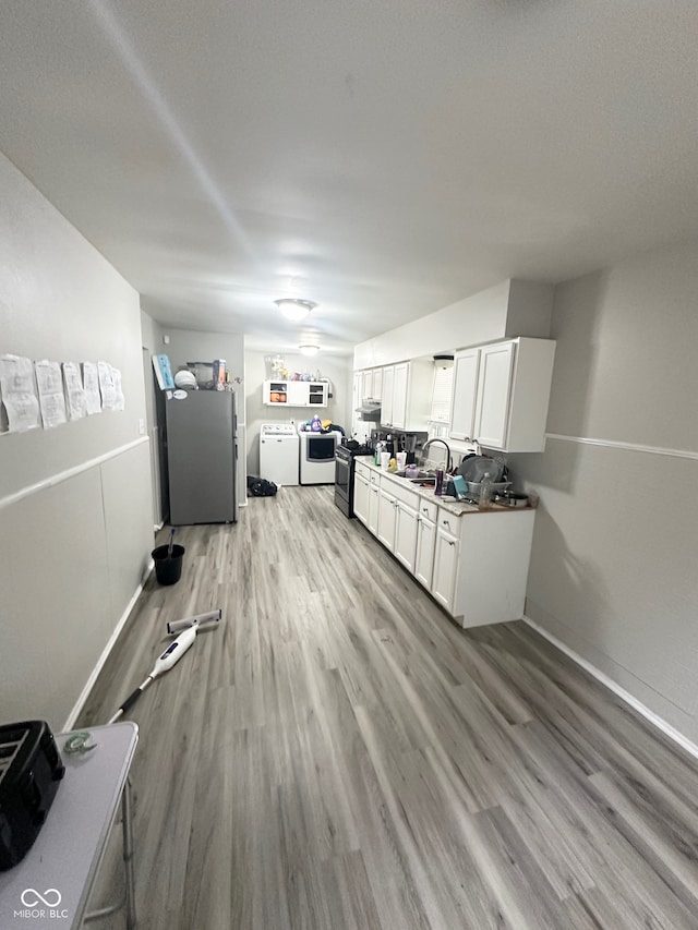 kitchen with washing machine and clothes dryer, sink, hardwood / wood-style flooring, white cabinetry, and appliances with stainless steel finishes