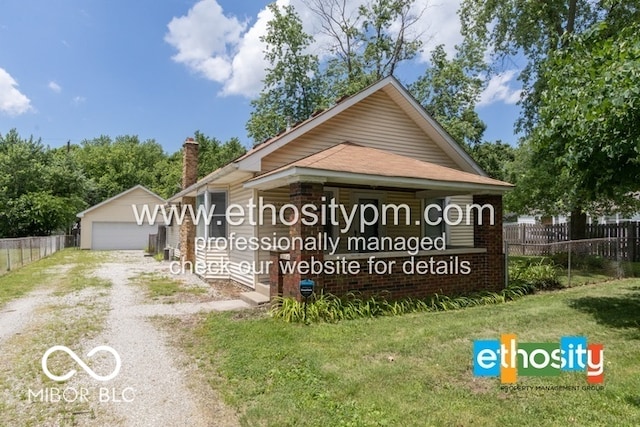 community sign featuring driveway, a detached garage, a yard, and fence