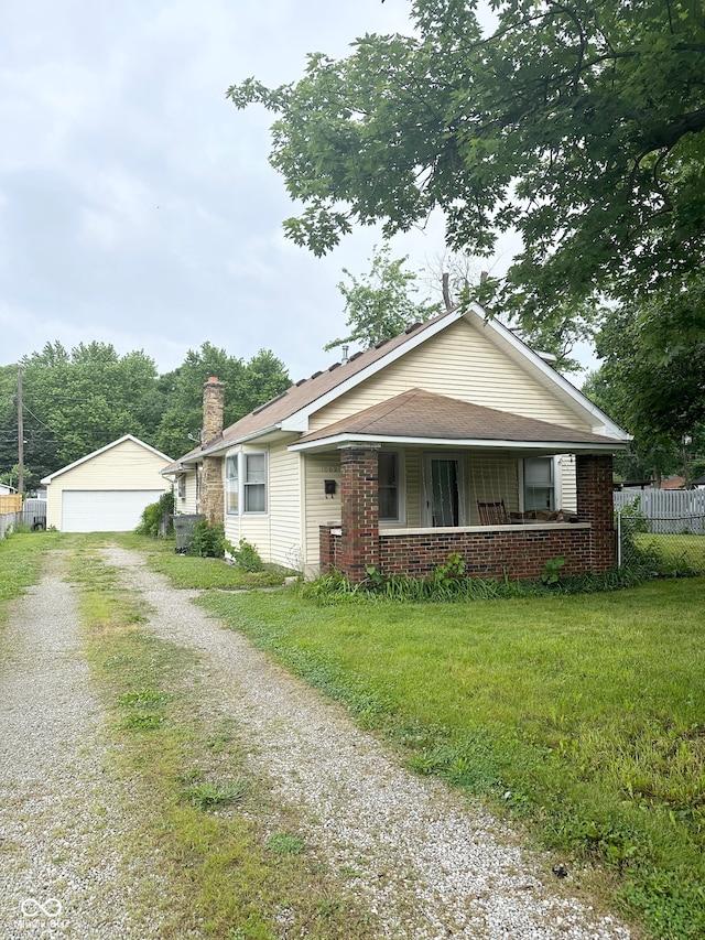 ranch-style home with a garage, a front yard, an outdoor structure, and a porch