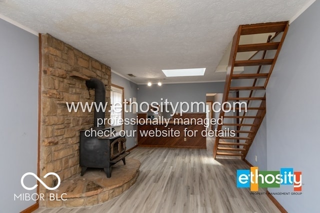 hallway featuring a skylight, ornamental molding, wood finished floors, and a textured ceiling