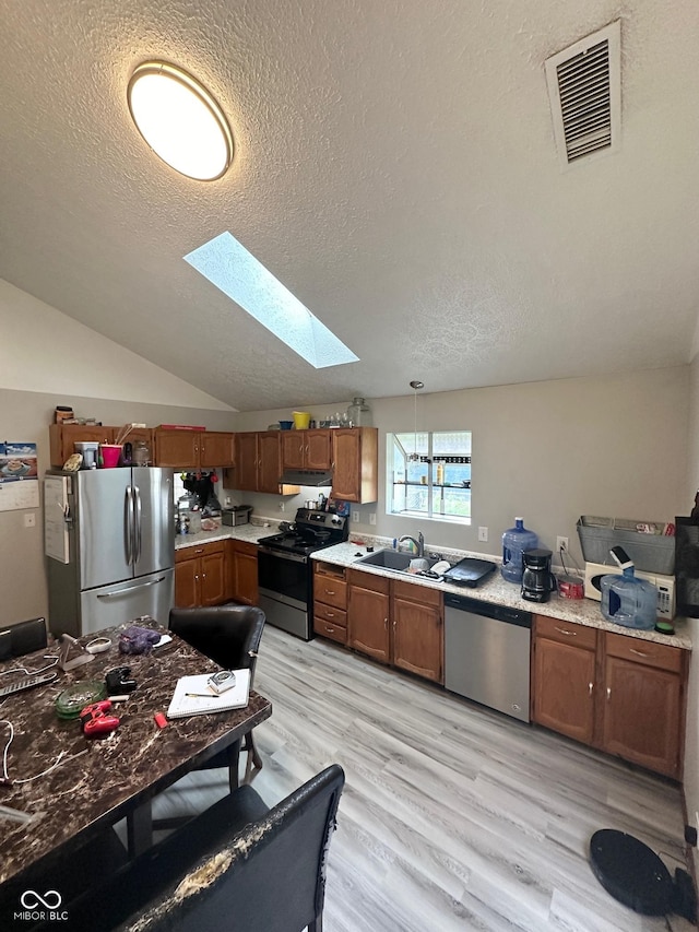 kitchen featuring light countertops, vaulted ceiling with skylight, visible vents, and appliances with stainless steel finishes