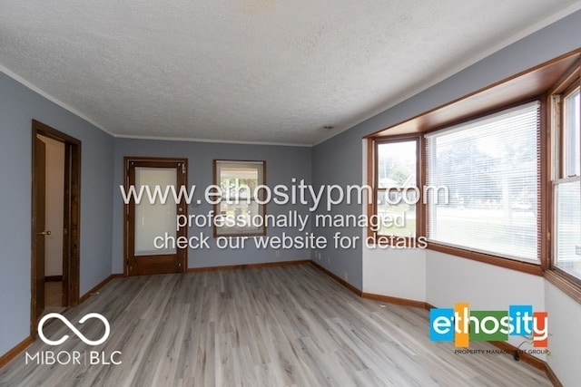 empty room featuring a healthy amount of sunlight, a textured ceiling, and hardwood / wood-style floors