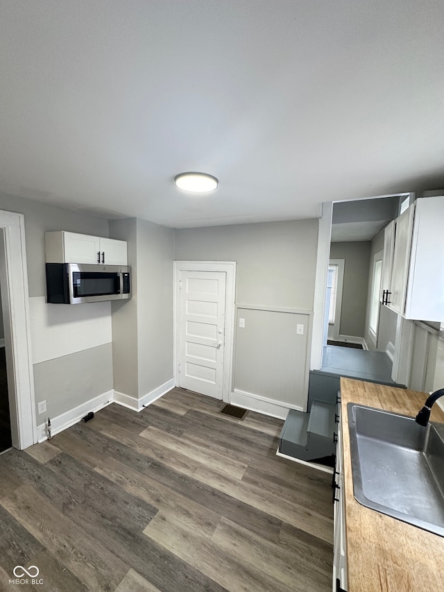 kitchen featuring dark wood-type flooring, sink, and white cabinetry