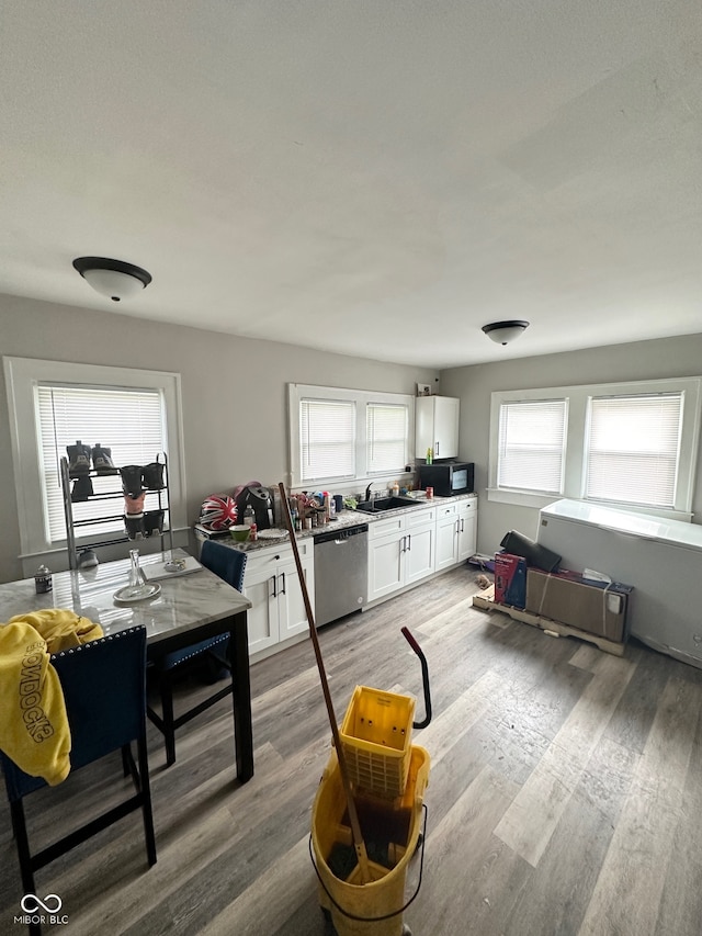 kitchen with plenty of natural light, dishwasher, white cabinets, and hardwood / wood-style flooring