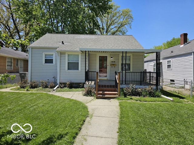 view of front of home featuring a front yard, roof with shingles, a porch, and fence