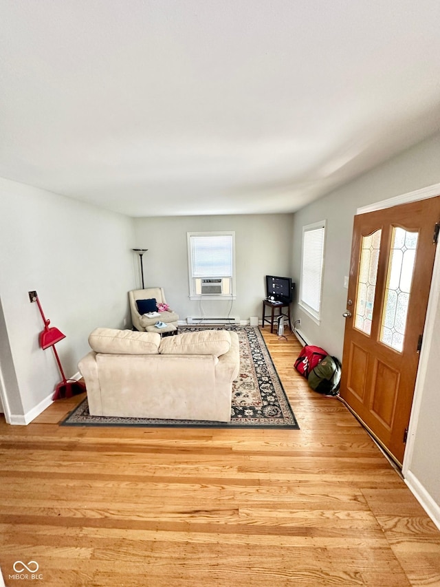 living area featuring baseboards, cooling unit, and wood finished floors
