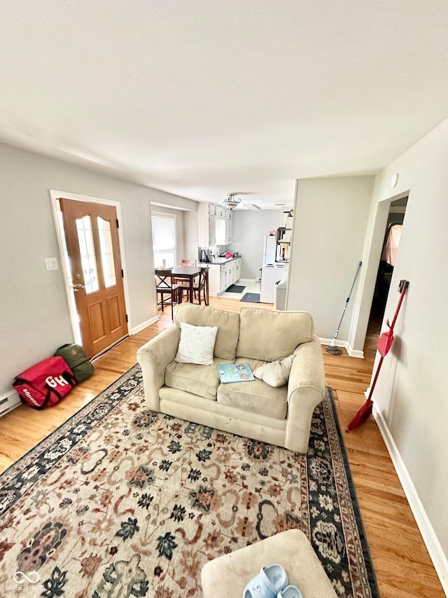 living area featuring baseboards and light wood-type flooring