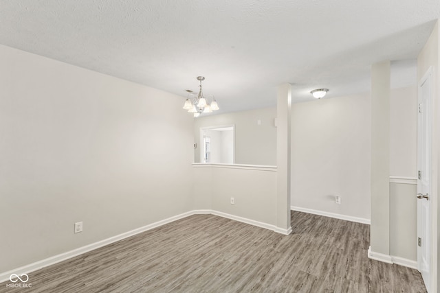 spare room featuring hardwood / wood-style floors, a textured ceiling, and an inviting chandelier