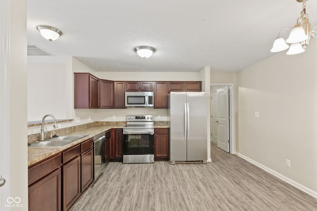 kitchen with decorative light fixtures, light hardwood / wood-style floors, sink, and appliances with stainless steel finishes