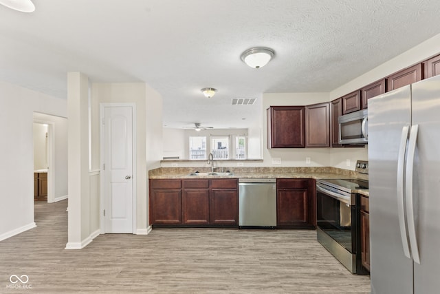 kitchen featuring sink, ceiling fan, a textured ceiling, light hardwood / wood-style floors, and stainless steel appliances