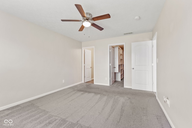 unfurnished bedroom with ceiling fan, ensuite bathroom, and light colored carpet