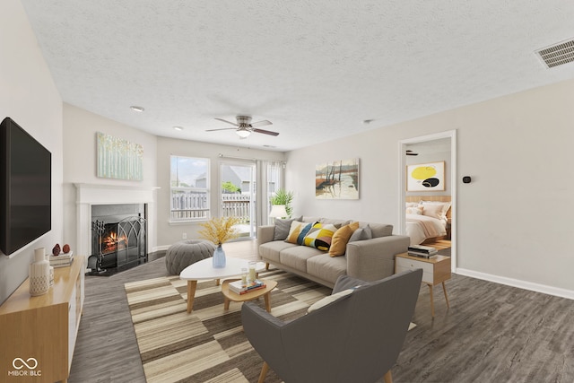 living room featuring dark hardwood / wood-style floors, ceiling fan, and a textured ceiling