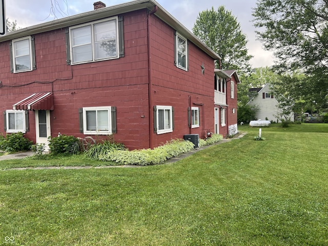 view of property exterior featuring central AC unit and a lawn