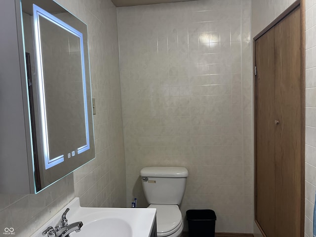 bathroom with tile walls, sink, and toilet