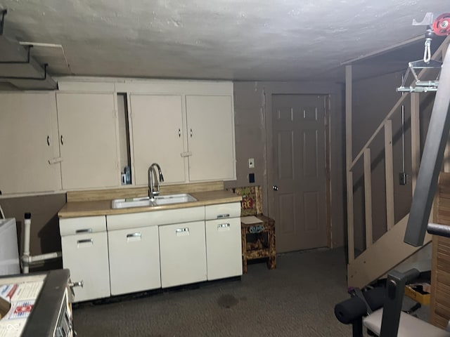 kitchen featuring white cabinetry, sink, and dark carpet