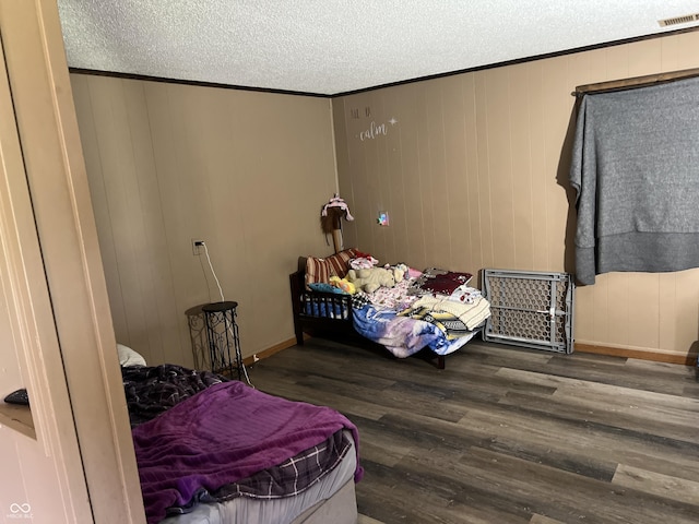 bedroom with crown molding, hardwood / wood-style floors, and a textured ceiling