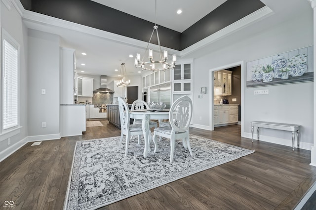 dining space featuring a chandelier, a raised ceiling, dark wood-type flooring, and crown molding