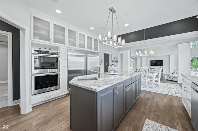 kitchen with gray cabinetry, a kitchen island with sink, sink, dark hardwood / wood-style floors, and appliances with stainless steel finishes