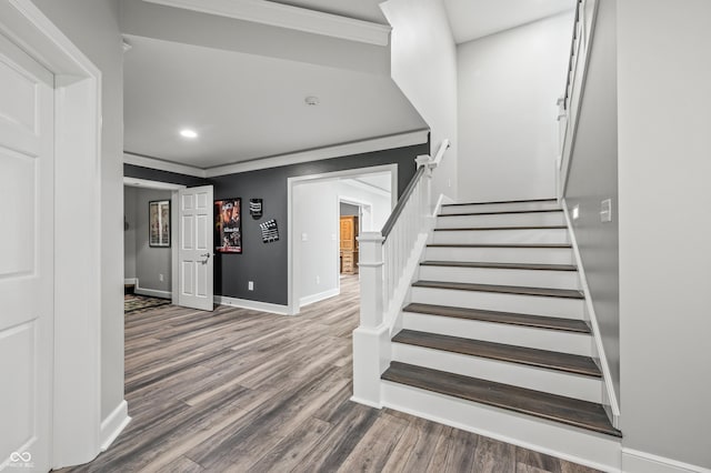 staircase featuring wood-type flooring and ornamental molding