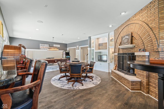 dining area featuring brick wall, dark wood-type flooring, billiards, and a brick fireplace