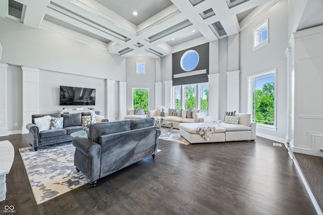 living room featuring beam ceiling, coffered ceiling, dark wood-type flooring, and a high ceiling