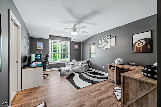 home office featuring ceiling fan, vaulted ceiling, and light hardwood / wood-style flooring