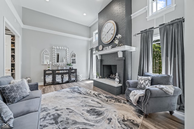 living room with a towering ceiling, hardwood / wood-style flooring, and a brick fireplace