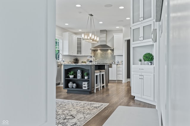 bar with wall chimney exhaust hood, dark wood-type flooring, white fridge, decorative light fixtures, and white cabinets