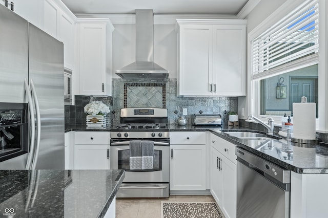 kitchen featuring white cabinetry, sink, wall chimney exhaust hood, stainless steel appliances, and dark stone counters