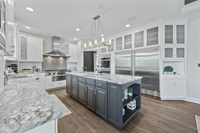 kitchen featuring appliances with stainless steel finishes, white cabinetry, and wall chimney exhaust hood