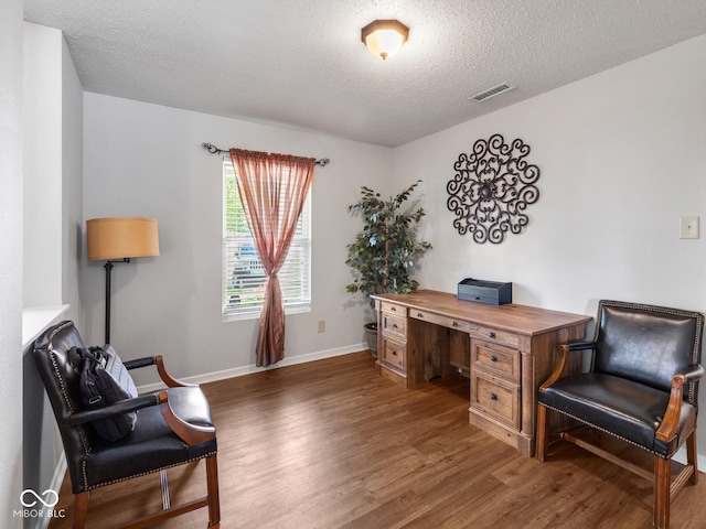 home office with a textured ceiling and dark wood-type flooring