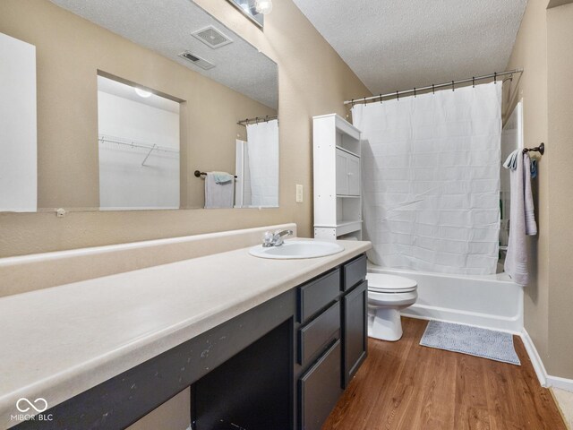 full bathroom featuring shower / bath combination with curtain, vanity, a textured ceiling, hardwood / wood-style floors, and toilet