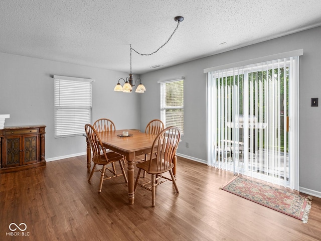 dining room with hardwood / wood-style flooring, a textured ceiling, and an inviting chandelier