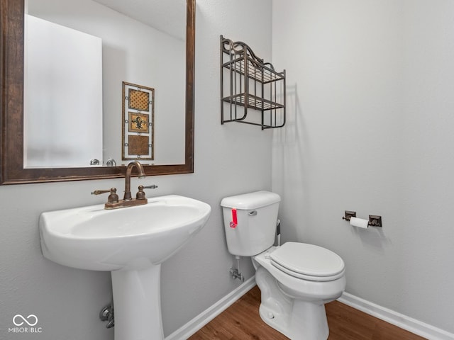 bathroom featuring wood-type flooring, toilet, and sink