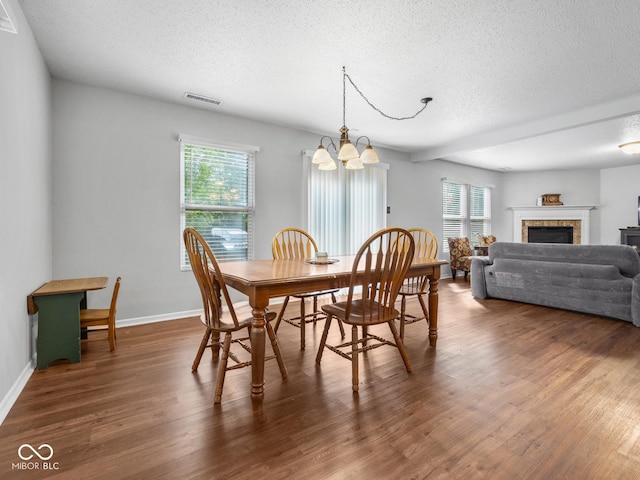 dining space featuring plenty of natural light, dark hardwood / wood-style flooring, and an inviting chandelier