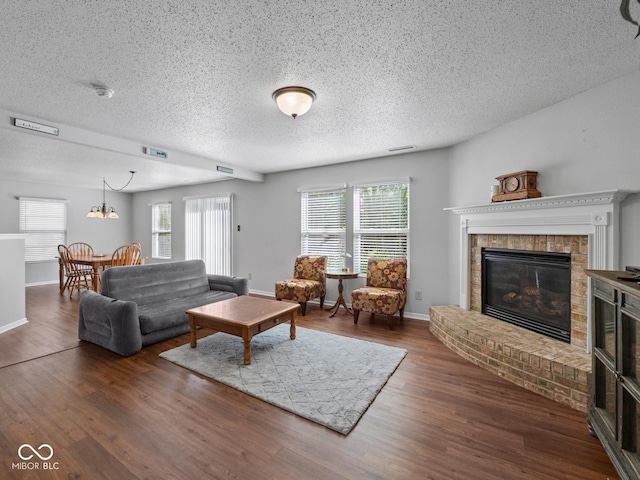 living room with dark wood-type flooring, a textured ceiling, and a brick fireplace