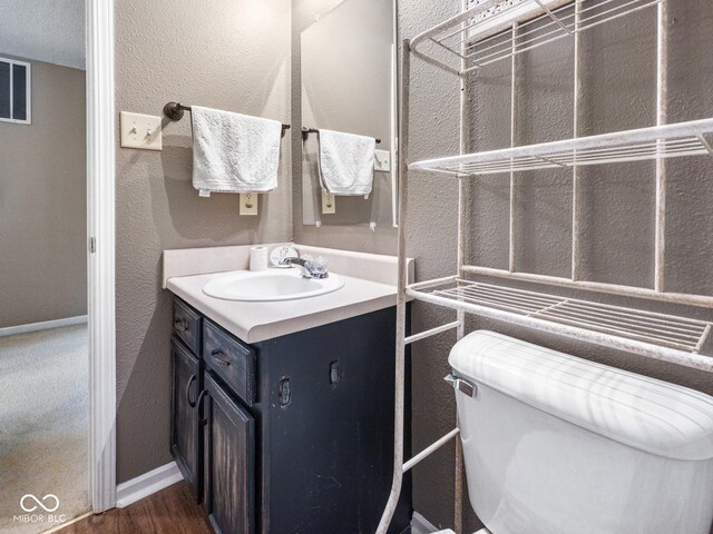 bathroom with wood-type flooring, vanity, and toilet