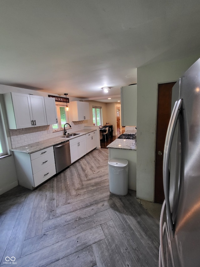 kitchen featuring parquet floors, light stone counters, sink, white cabinets, and appliances with stainless steel finishes