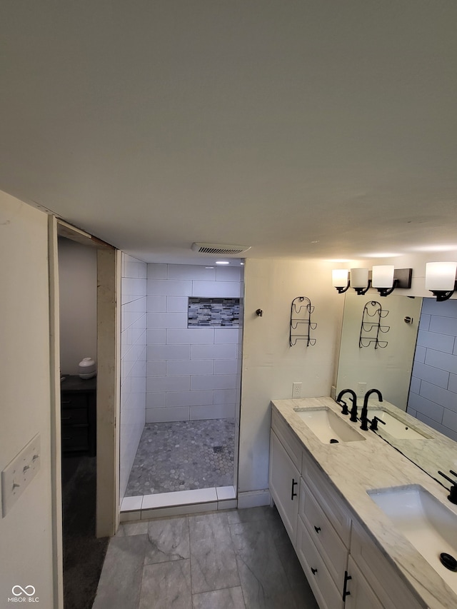 bathroom with dual vanity, a tile shower, and tile floors